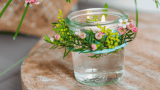 Tischdeko Muttertag, kleines Glas mit Schwimmkerze und Blütenkranz