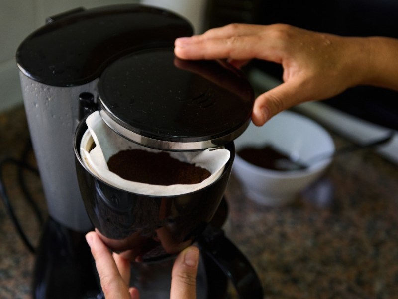 jemand bereitet Kaffee in einer Filterkaffeemaschine zu