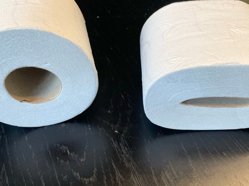 Zwei Rollen Klopapier liegen nebeinander auf einem Tisch.