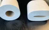Zwei Rollen Klopapier liegen nebeinander auf einem Tisch.