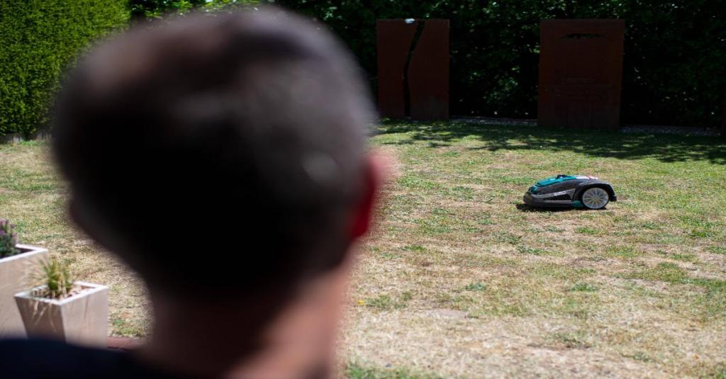 Ein Mann starrt auf seinen Mähroboter.